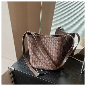 Detail of dark brown woven bucket bag featuring intricate texture and adjustable strap