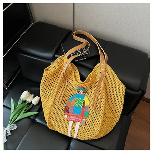 Detail of yellow knit tote bag featuring a character embroidery and leather tassels