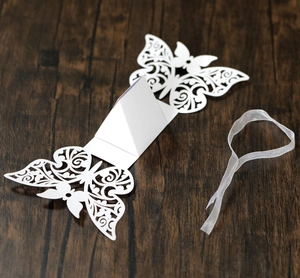 Laser cut butterfly wedding candy box with elegant white ribbon on dark wood background