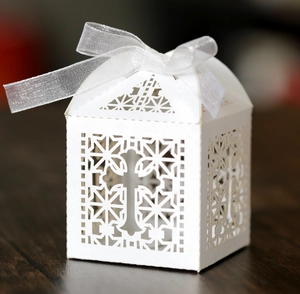 Detailed laser-cut white favor box with cross design and semi-transparent ribbon