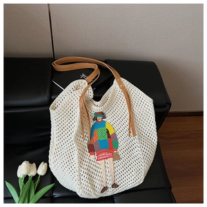 Detail of white knit tote bag featuring colorful cartoon embroidery and brown leather straps