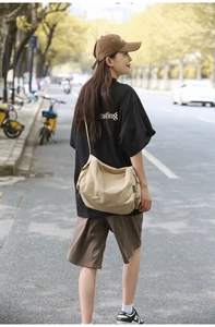 Détail du grand sac bandoulière beige avec sangle réglable et étiquette latérale