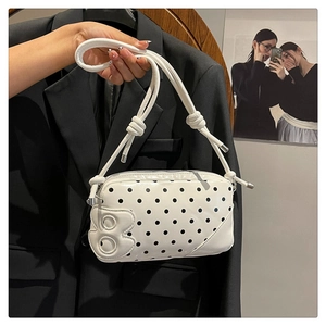 Close-up of a white polka dot shoulder bag featuring a raised metal B logo and knotted strap