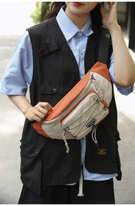 Detail of orange and beige nylon crossbody chest bag showing adjustable strap and drawstrings