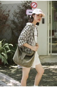 Olive green canvas hobo bag with large capacity shown in an outdoor casual street style
