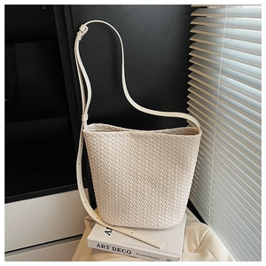 Detail of beige woven bucket bag with lattice texture resting on art books
