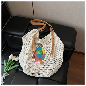 Detail of white crochet tote bag with cartoon patchwork embroidery and brown leather strap