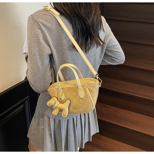 Detailansicht einer beigen Handtasche aus Canvas mit Monogramm und Hund-Anhänger