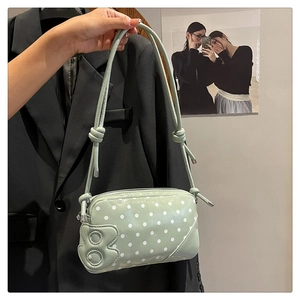 Close-up of mint green polka dot handbag with a 3D letter B patch and adjustable strap