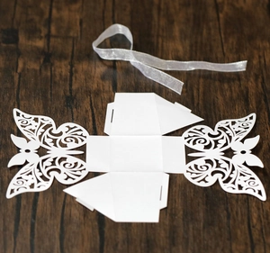 Detail of laser cut butterfly wedding candy box in white pearlescent paper with silver ribbon