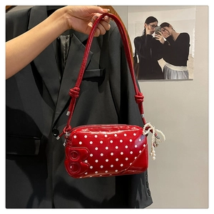 Detail of red polka dot patent leather shoulder bag with pearl heart charm and B logo
