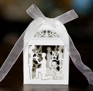 Detail of white laser-cut wedding candy box with romantic silhouette and organza ribbon