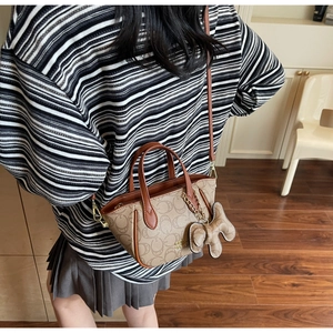 Nahaufnahme der braunen Präge-Handtasche mit Bärenanhänger und Schultergurt