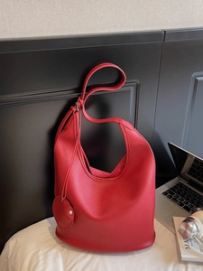Red pebbled leather hobo tote bag with detachable round coin purse on a white bed