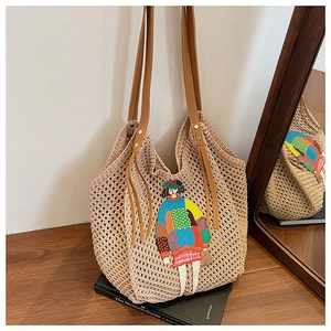 Detail of crochet tote bag featuring colorful female embroidery and leather tassels
