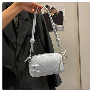 Close-up of light blue polka dot bag with glossy finish and elegant pearl tassel charm