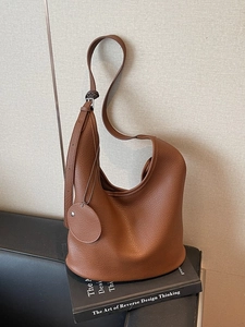 Minimalist brown lychee leather hobo tote bag on book with adjustable shoulder strap