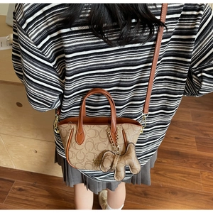 Detail der beigen Monogramm-Handtasche mit braunem Lederriemen und Hundeanhänger