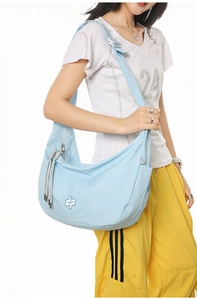 Detailed view of light blue checkered dumpling bag with crossbody strap and logo