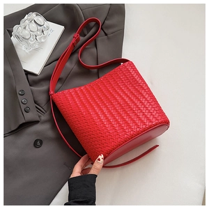 Detail of red woven bucket bag showing premium leather texture and long shoulder strap