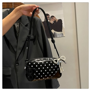 Detailed shot of a black polka dot crossbody bag with pearl bow and B-logo accent