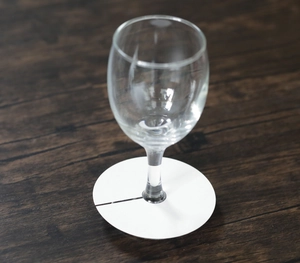 Gouttelette en carton blanc pour verre à vin posée sur un pied de verre élégant