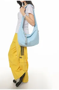 Detail of light blue checkered crossbody bag with metal logo and tassel on a model