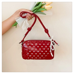Detail of red polka dot handbag featuring a 3D letter B and a white pearl bow charm