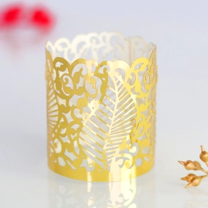 Detailed view of golden laser-cut paper candle wraps with intricate leaf vine patterns