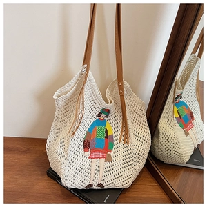 Detail of knit tote bag featuring colorful cartoon embroidery and brown leather fringe