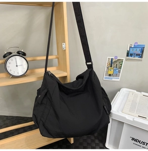 Détail du sac messager en nylon noir avec bandoulière réglable et poche latérale