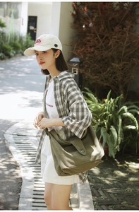 Olive green large canvas crossbody bag shown on a model for a casual outdoor lifestyle look