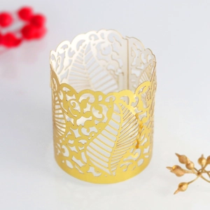 Detail showing golden laser-cut hollow tea light wrap with intricate floral leaf patterns