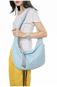 Detailed side view of large light blue gingham hobo bag with tassel and embroidery on model