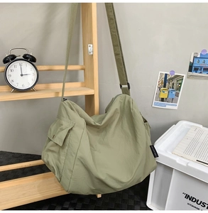 Vue détaillée du grand sac cabas en toile vert olive accroché sur un support en bois