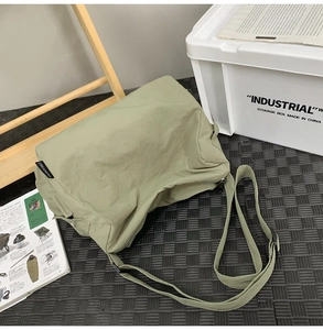 Vue de dessus d'un sac bandoulière en nylon vert avocat avec sangle réglable sur tapis