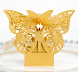 Detailed close-up of a golden laser-cut butterfly wedding favor box with a silk ribbon bow
