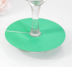 Détail macro d'un marque-verre en papier vert placé sur le pied d'un verre
