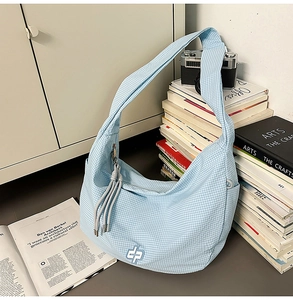 Detail of light blue gingham hobo bag showing plaid texture and white embroidered logo