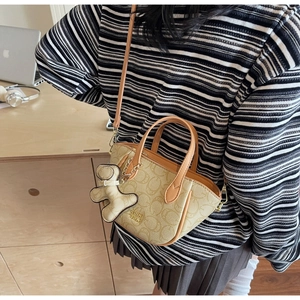 Nahaufnahme beige Umhängetasche mit geometrischem Muster und süßem Bärenanhänger