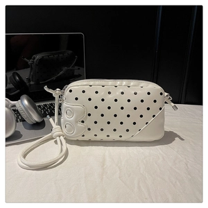 Polka dot crossbody bag with B-patch shown next to a laptop in a modern desk setting