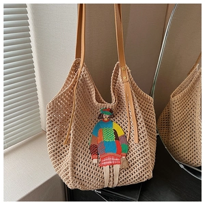 Detail of straw woven tote bag featuring a colorful cartoon embroidery and leather strap