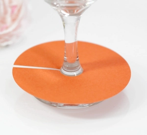 Vue macro d'un marque-place en papier orange pour verre à vin avec fente sur verre transparent