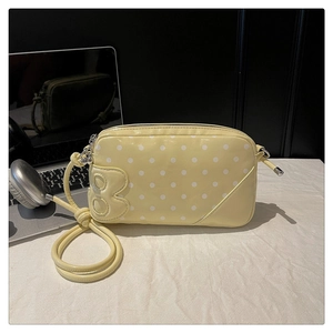 Detailed shot of yellow polka dot crossbody bag with silver hardware and B-logo patch