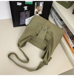 Detailed view of an olive green canvas crossbody bag featuring a metal twist lock closure