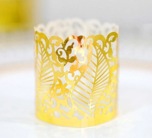 Macro view of gold laser-cut paper candle wraps with leaf and vine textures for parties