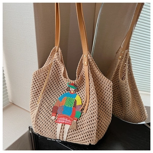 Detail of beige crochet tote bag featuring colorful girl embroidery and leather straps
