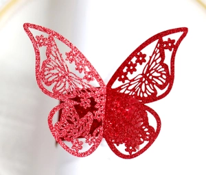 Detalle de servilletero de mariposa roja con purpurina y patrón hueco cortado por láser