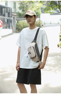 Outdoor street view of a beige and grey techwear crossbody bag with tactical drawstrings