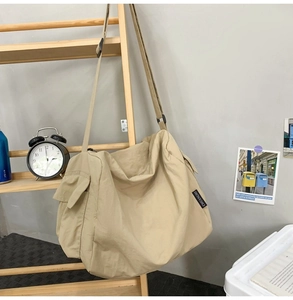 Détail du sac fourre-tout en nylon beige montrant le tissu texturé et l'étiquette tissée